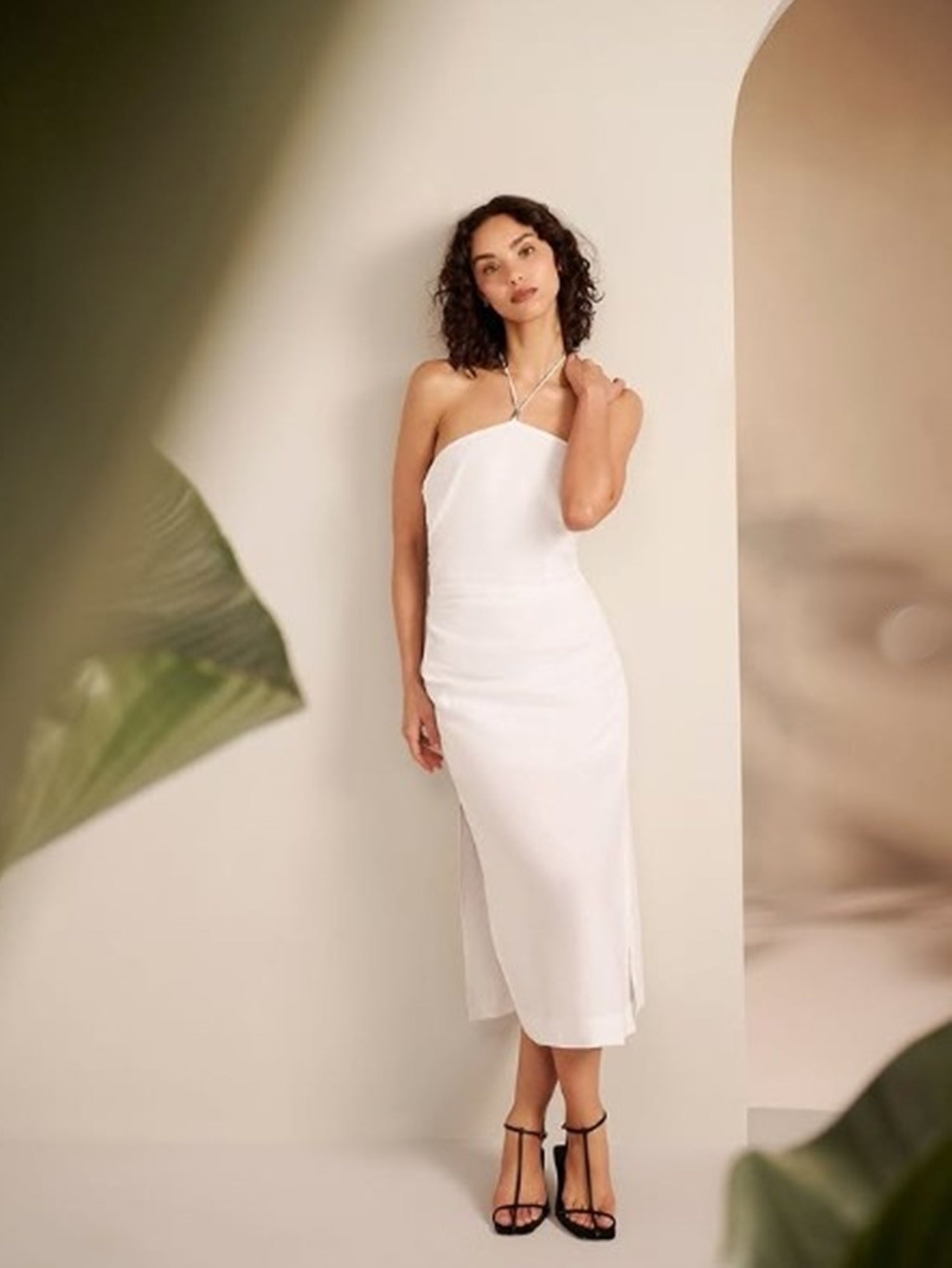Woman wearing a white dress standing against a plain background