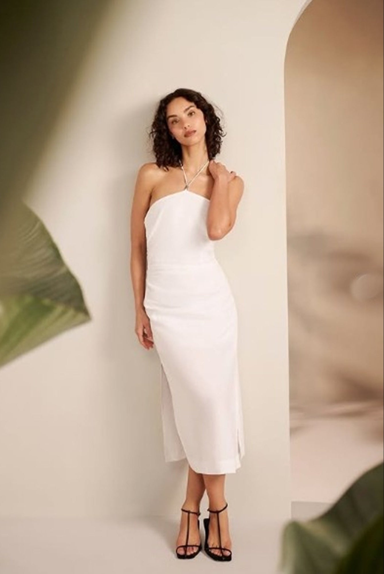Woman wearing a white dress standing against a plain background
