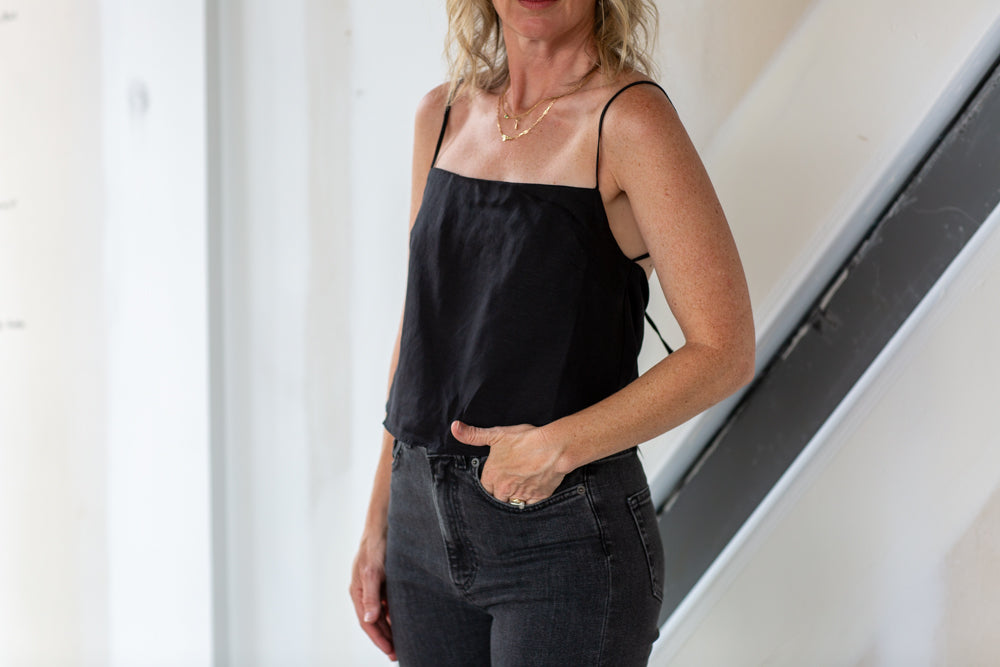 Woman wearing a black top and black pants standing indoors.