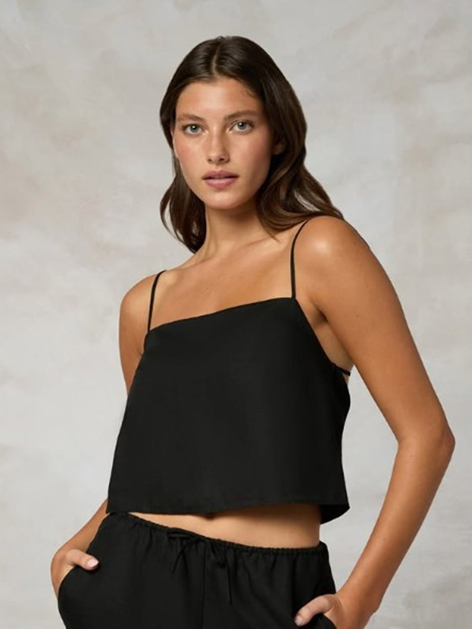 Woman wearing a black one-shoulder top against a neutral background