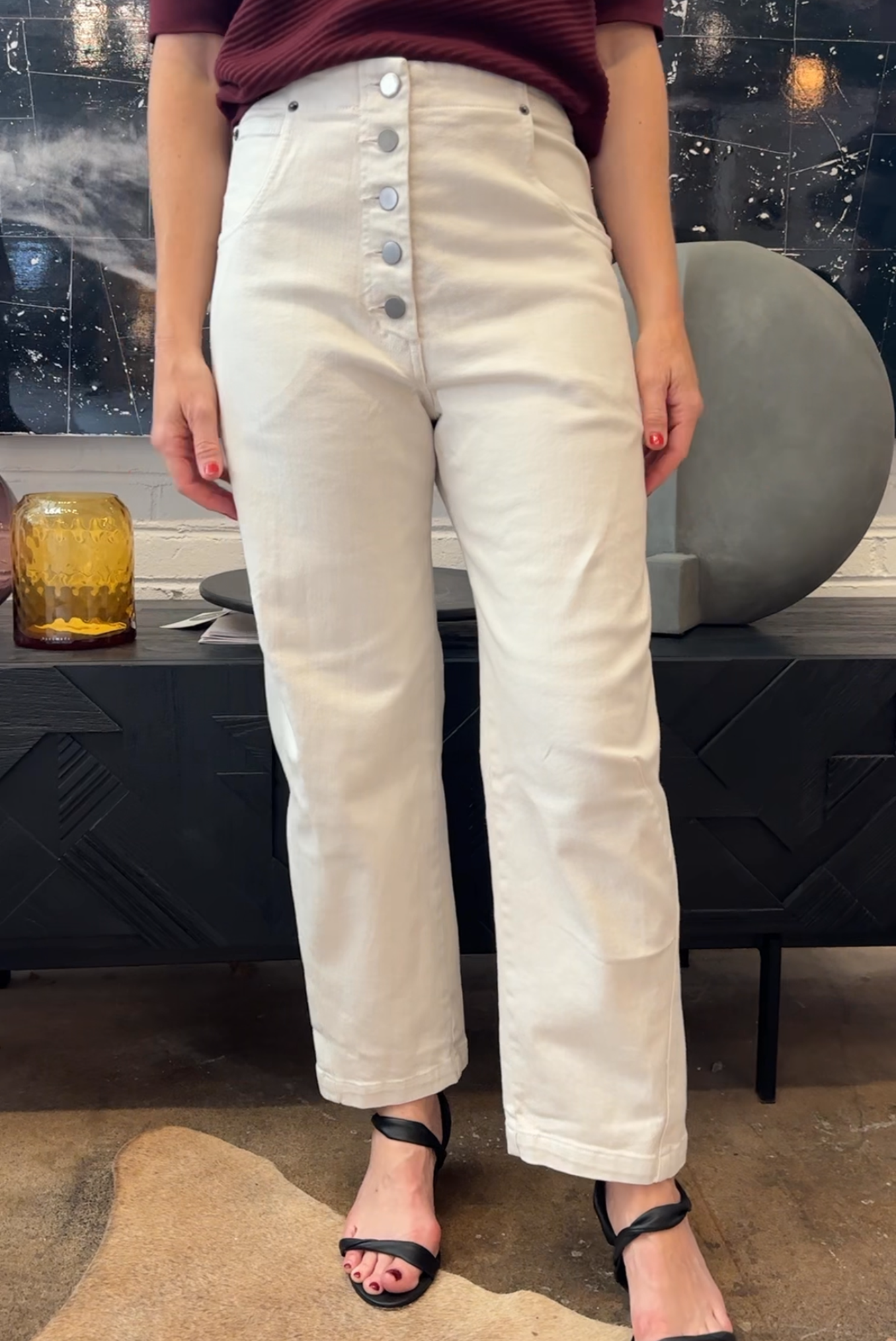 Person wearing white pants with button details in an indoor setting