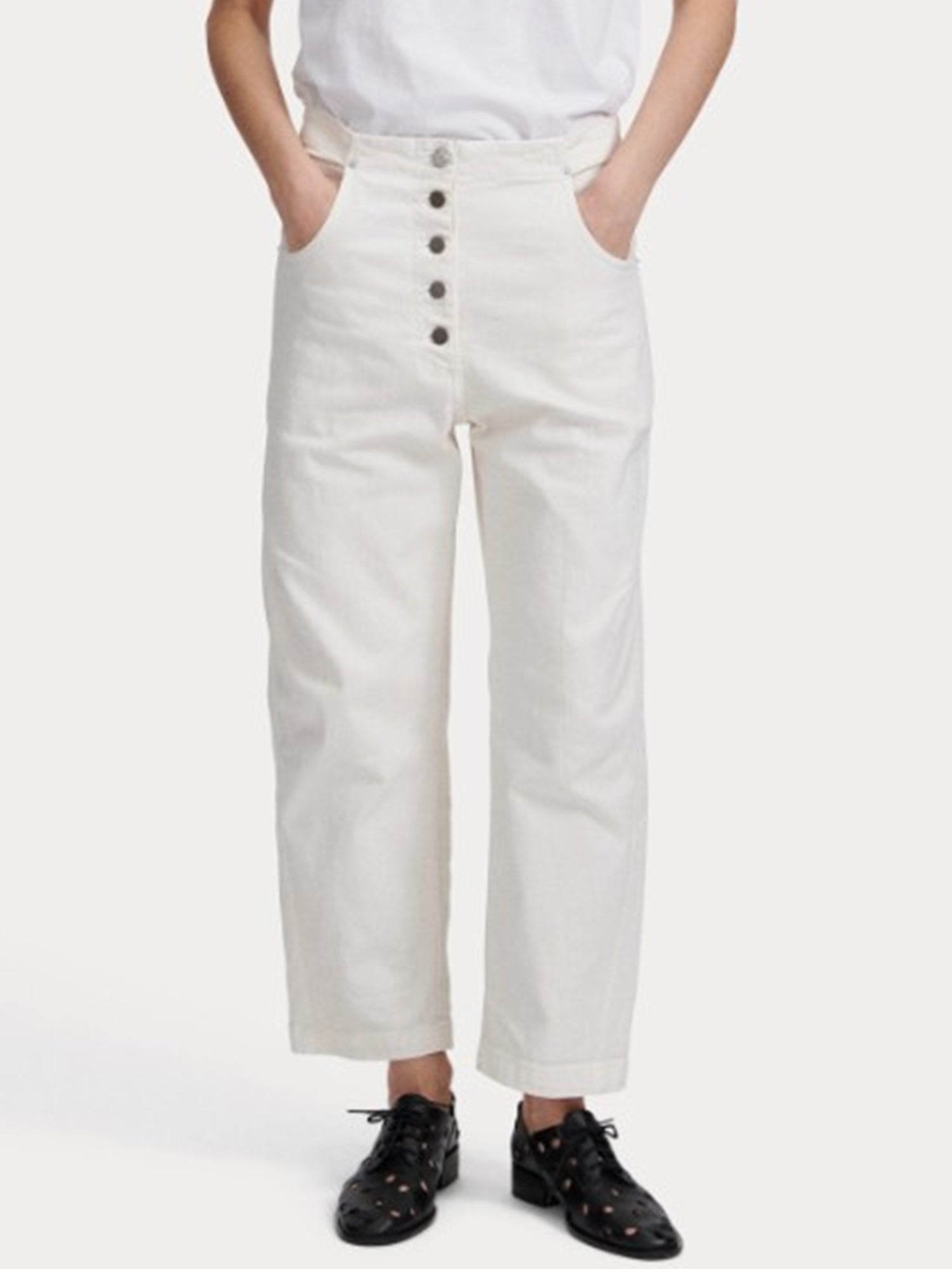 Person wearing white high-waisted pants with buttons on a white background
