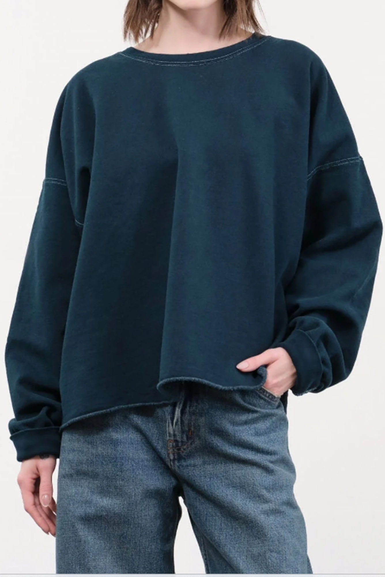 Person wearing a dark blue oversized sweatshirt and jeans on a white background