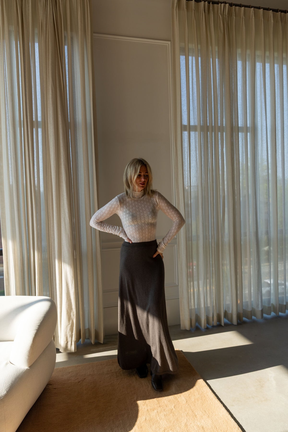 Lisa Yang Adrienne Skirt in deep walnut with a Sablyn Rhea turtleneck, full-length view in a sunlit room
