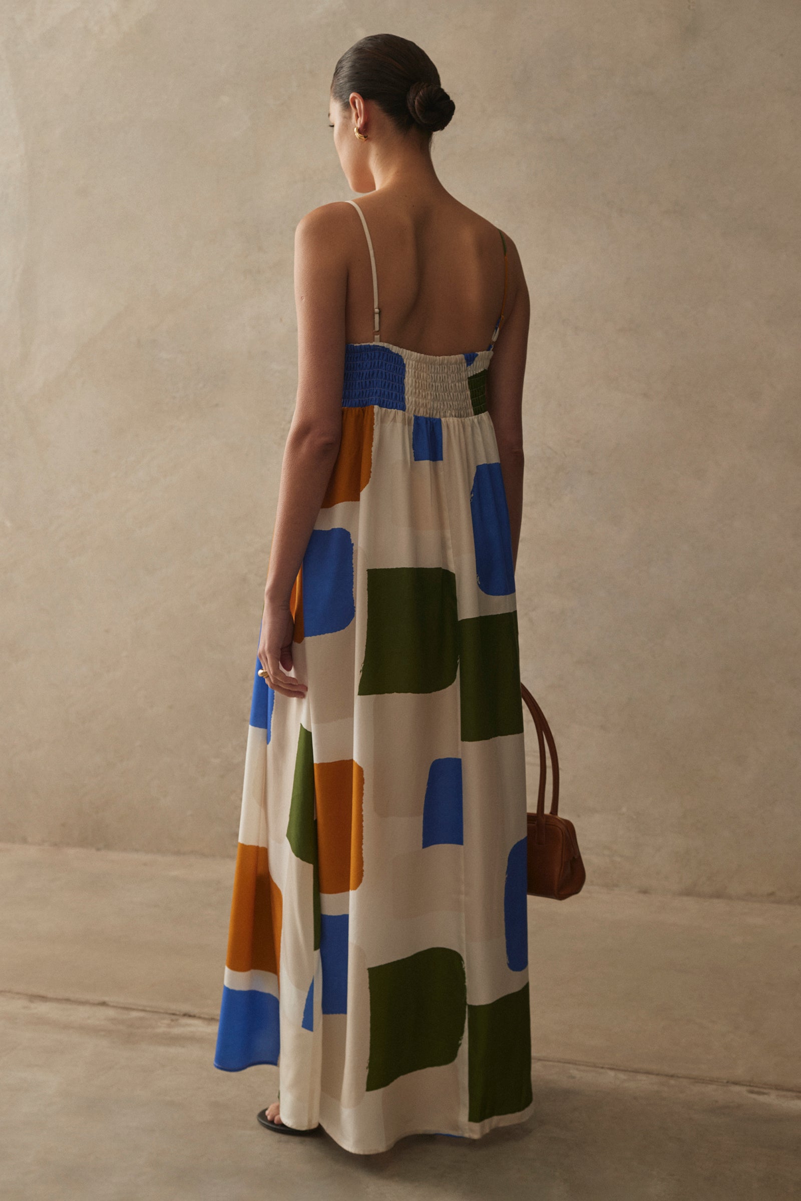 Woman wearing a colorful geometric-patterned dress against a plain background