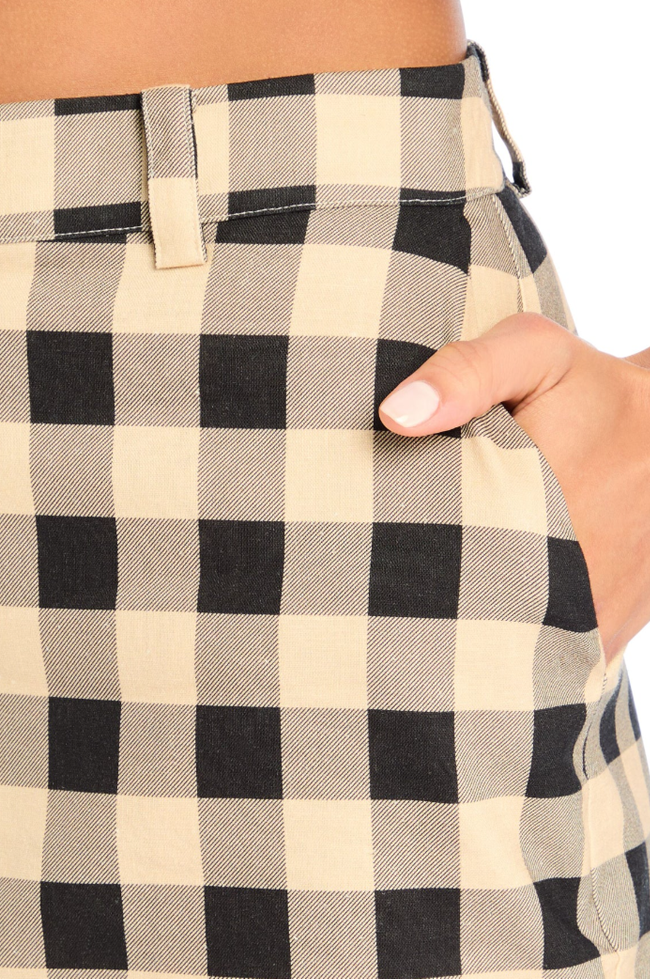 Close-up of a person wearing a black and beige checkered shirt with a hand adjusting the collar.