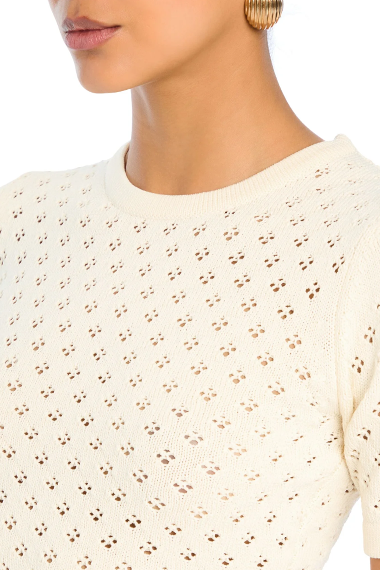 Close-up of a person wearing a cream-colored blouse with a subtle pattern.