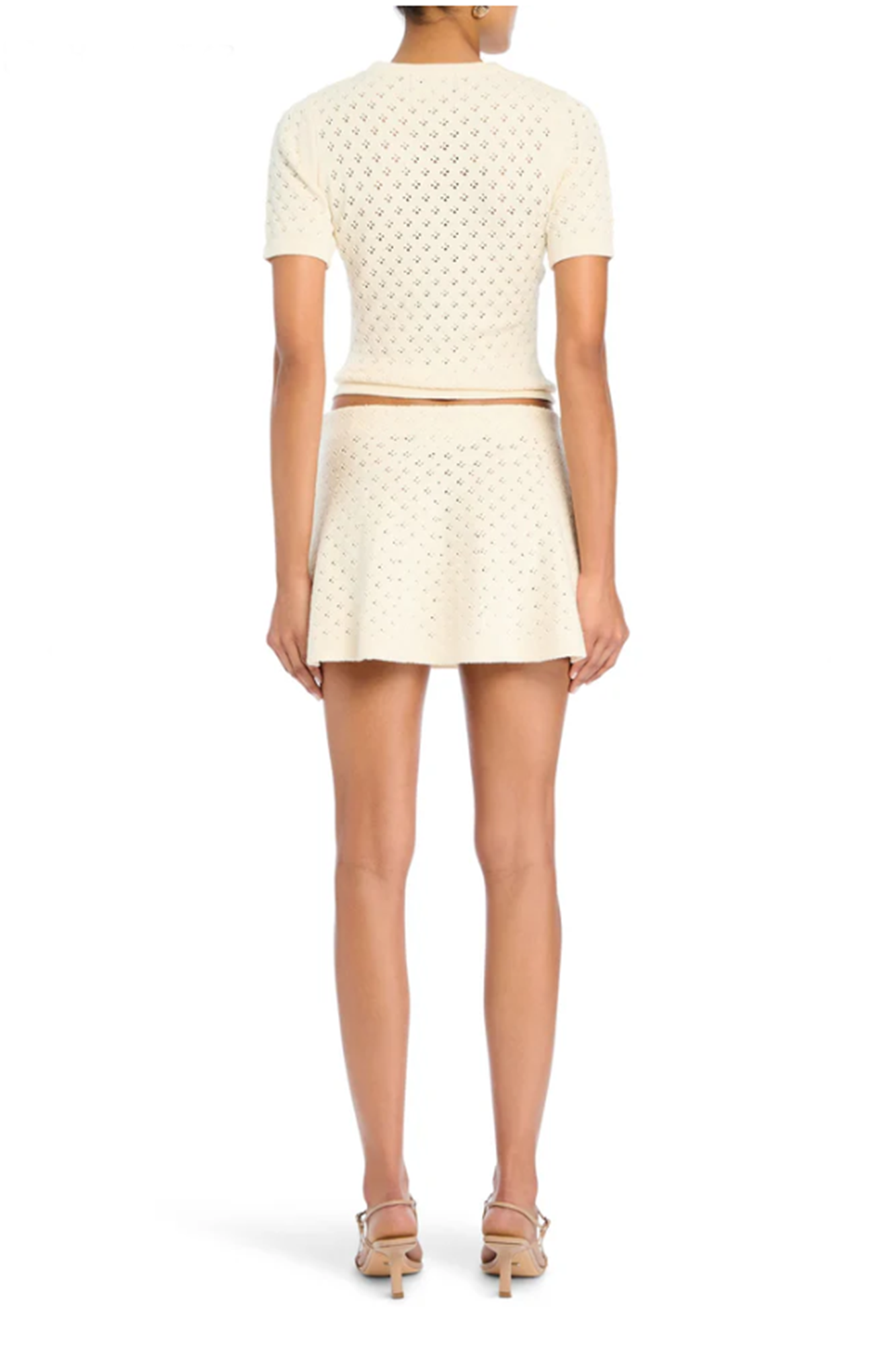 Woman wearing a cream-colored outfit with a patterned top and skirt on a white background