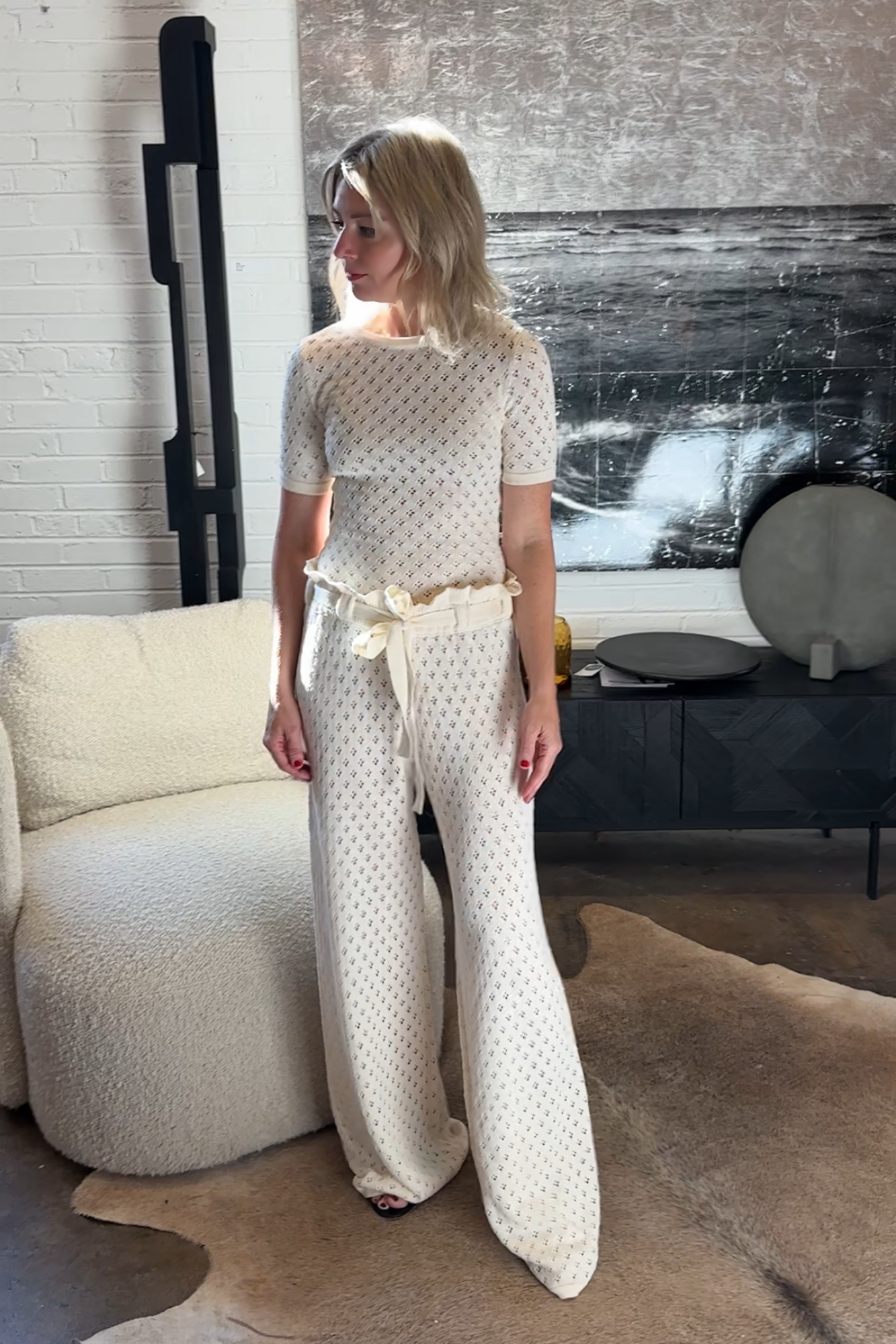 Woman in a knit outfit standing in a living room.