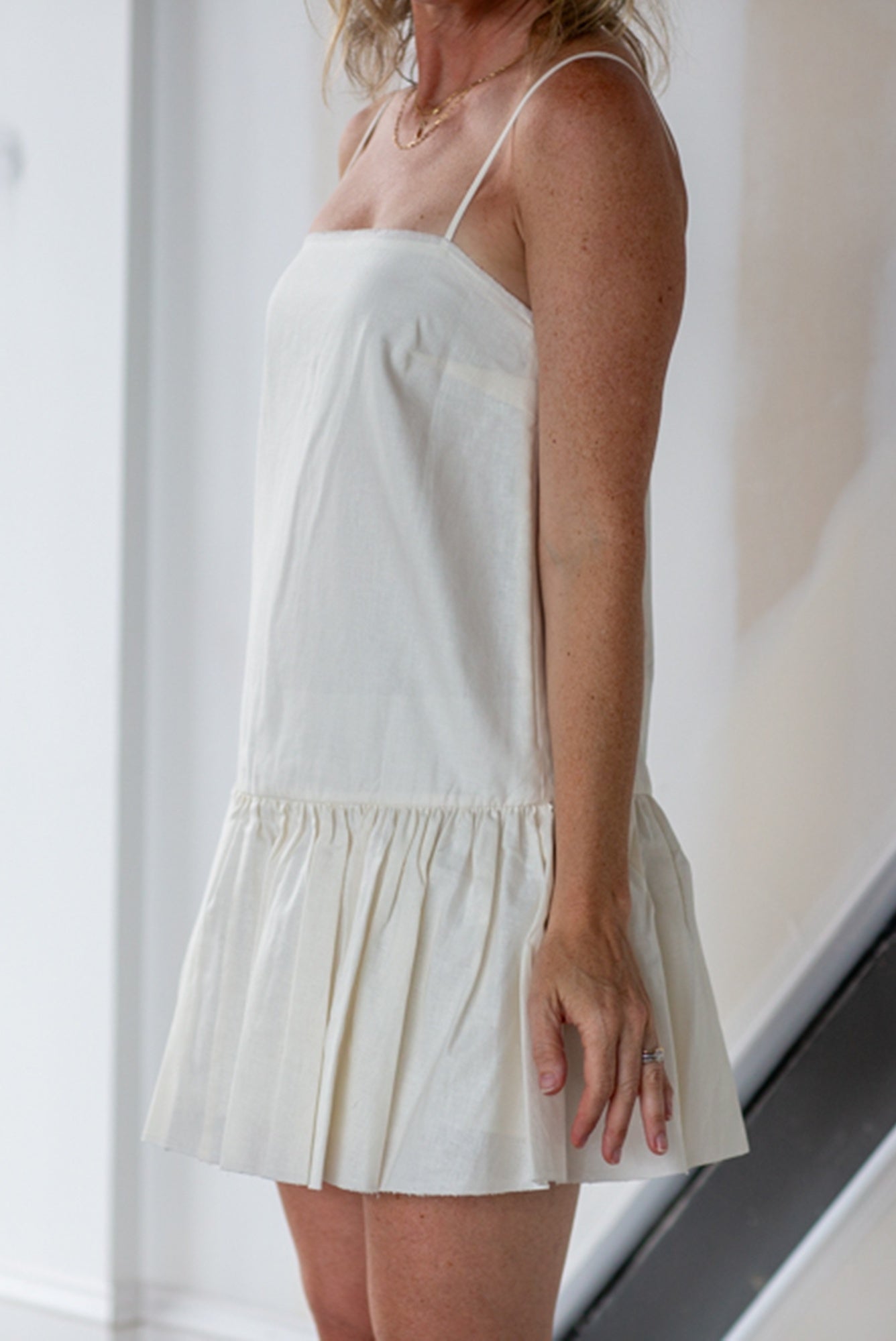 Woman wearing a white dress against a neutral background