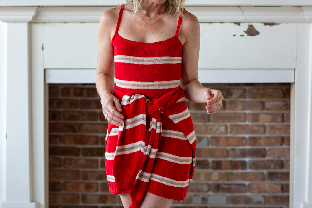 Woman wearing a red and white striped dress in front of a brick wall.