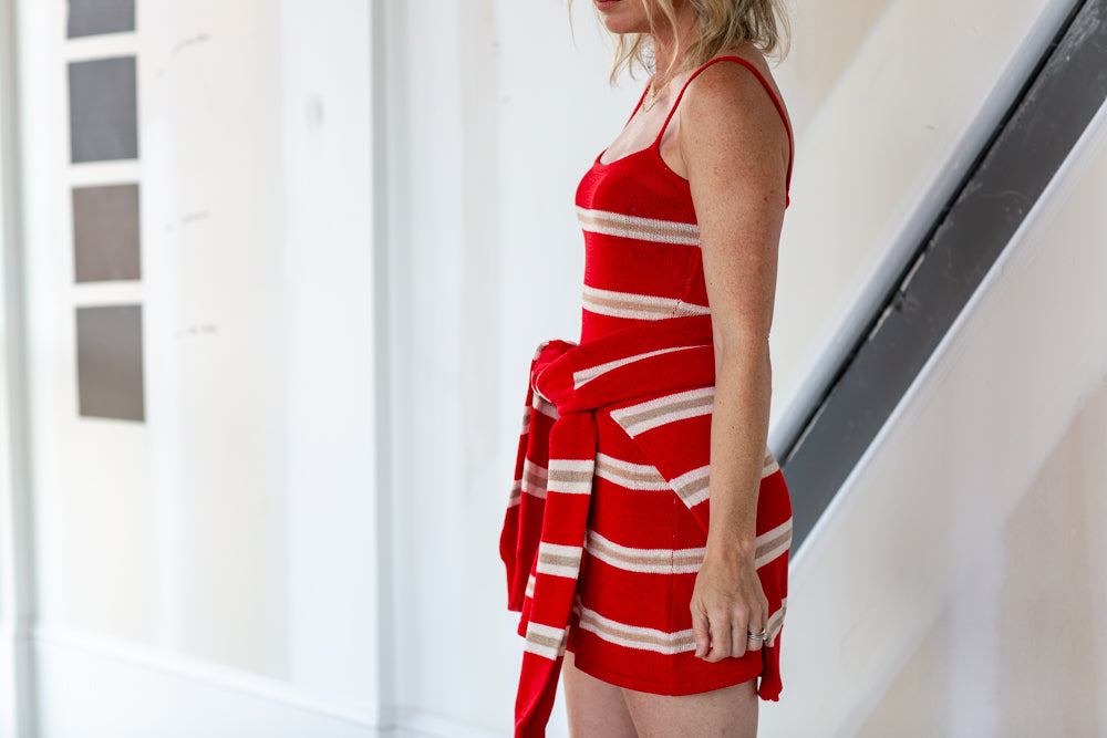 Woman wearing a red and white striped dress standing indoors.