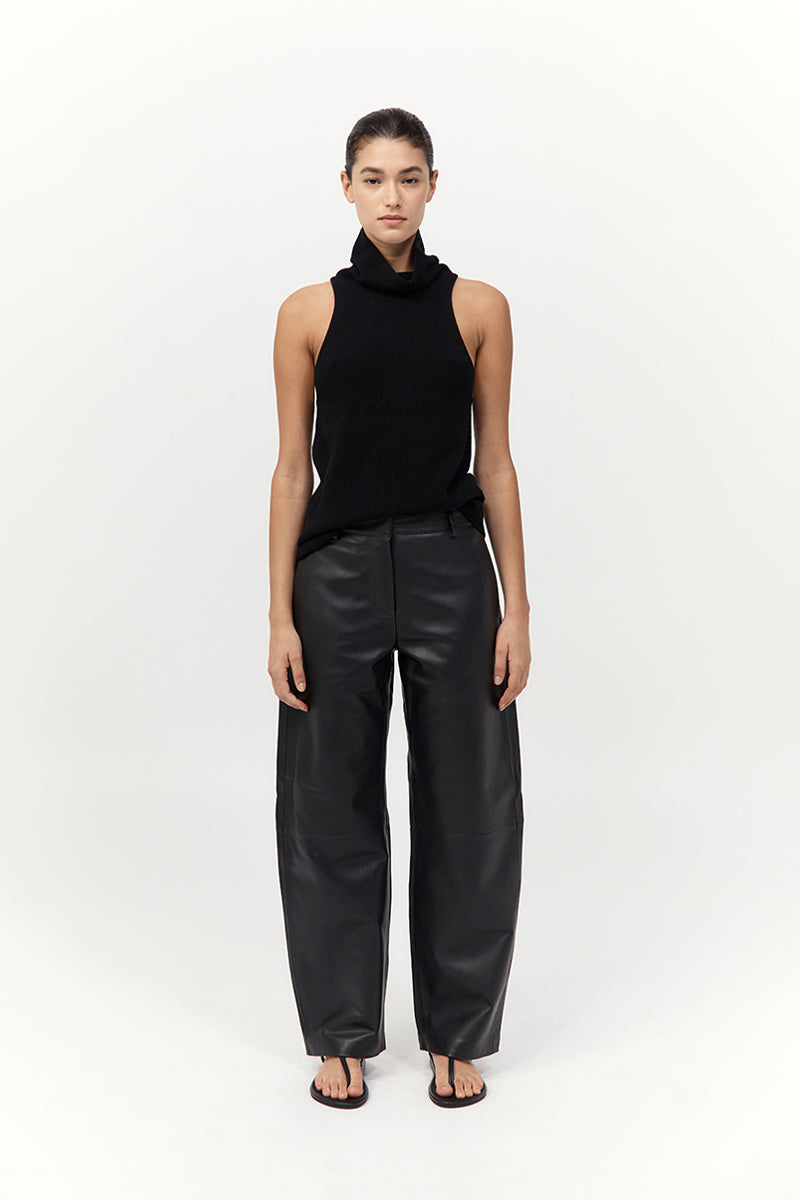 Person wearing a black sleeveless top and black pants on a white background