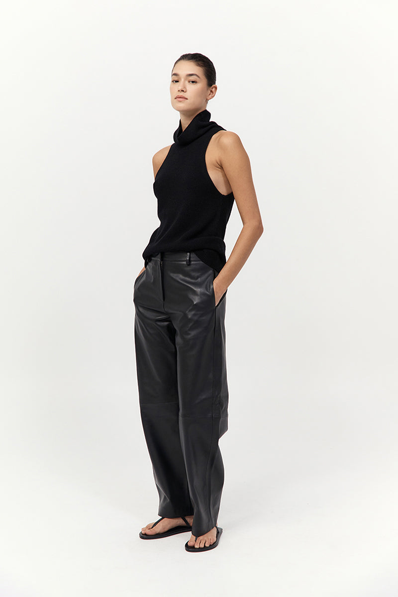 Woman wearing a black sleeveless top and black leather pants on a white background