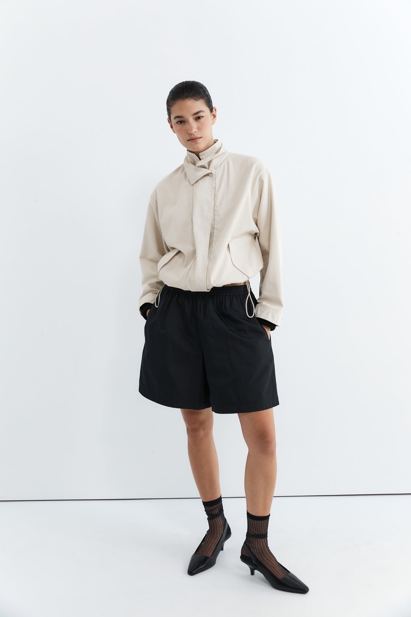 Person wearing a beige shirt and black shorts on a white background