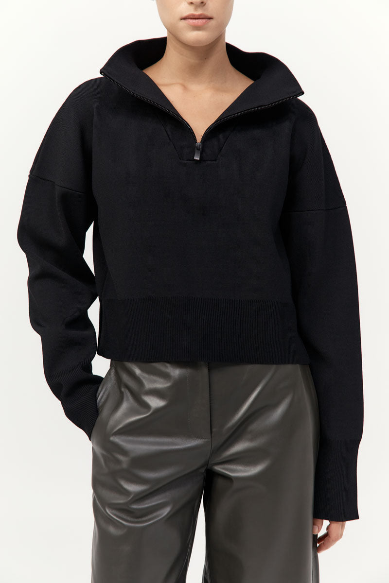 Person wearing a black hoodie and gray pants on a white background