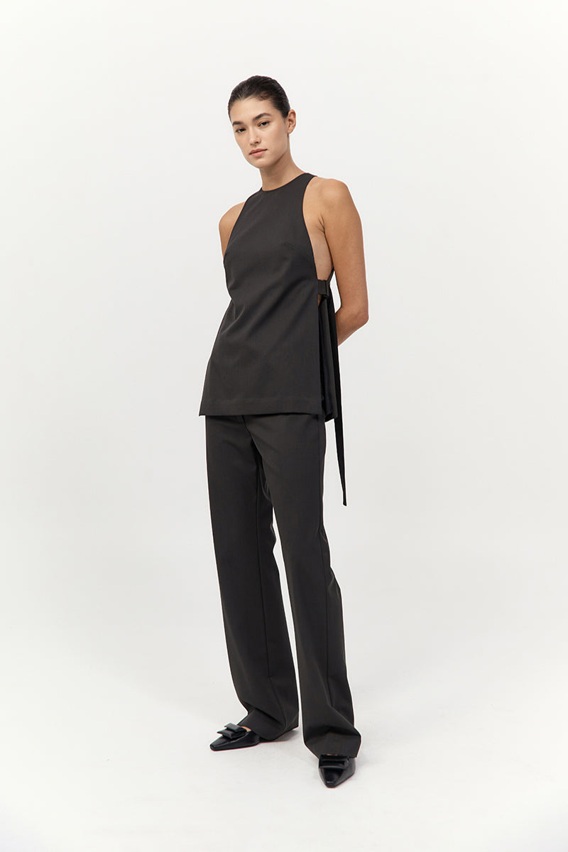 Woman wearing a black sleeveless top and pants on a white background
