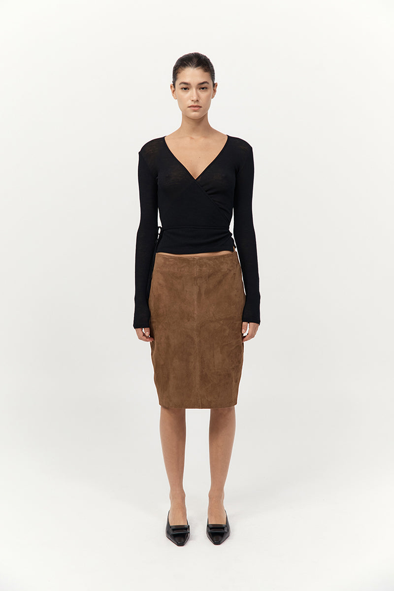 Woman wearing a black top and brown skirt on a white background