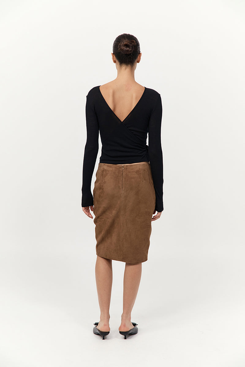 Person wearing a black long-sleeve top and brown skirt on a white background