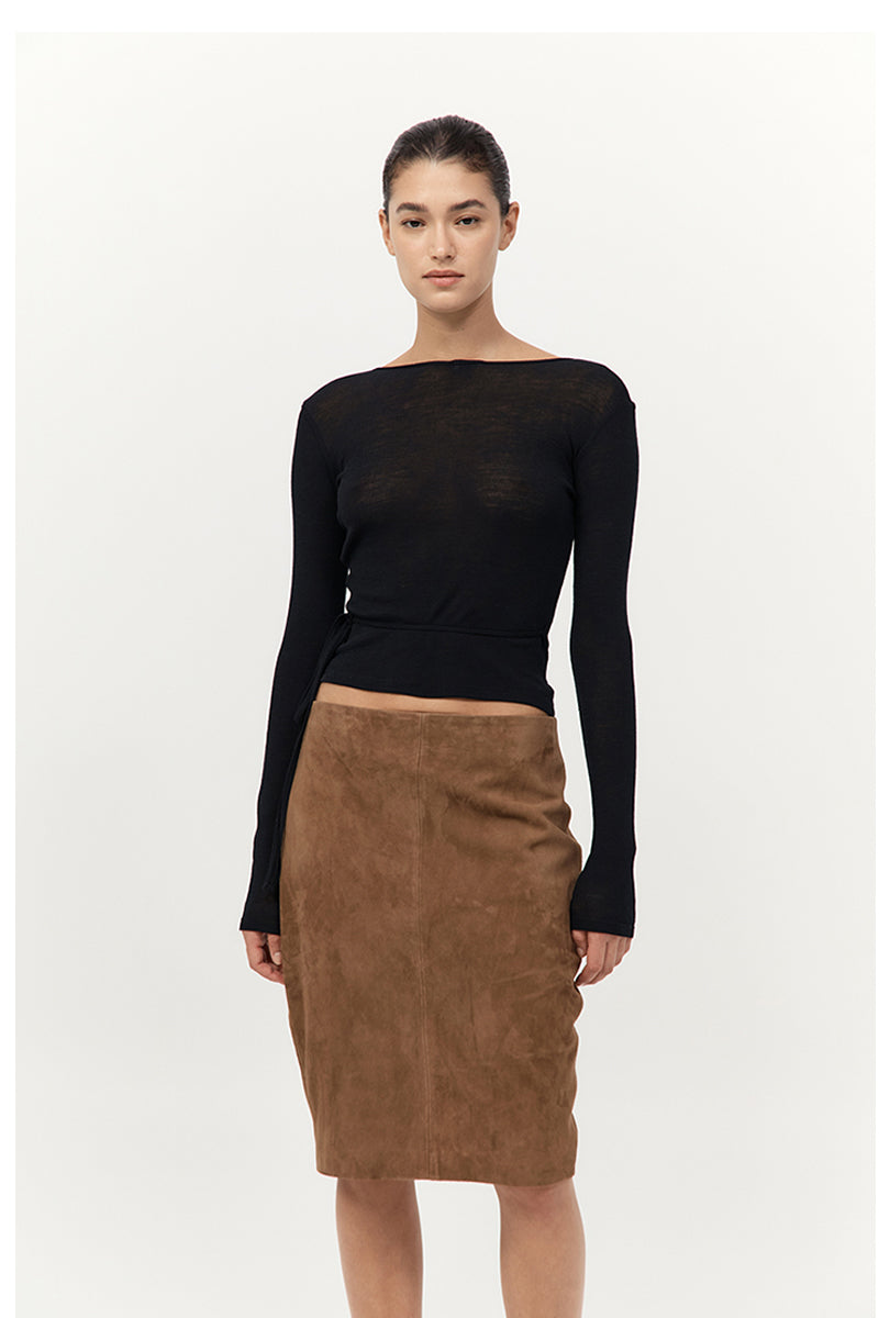 Woman wearing a black long-sleeve top and brown suede skirt on a white background