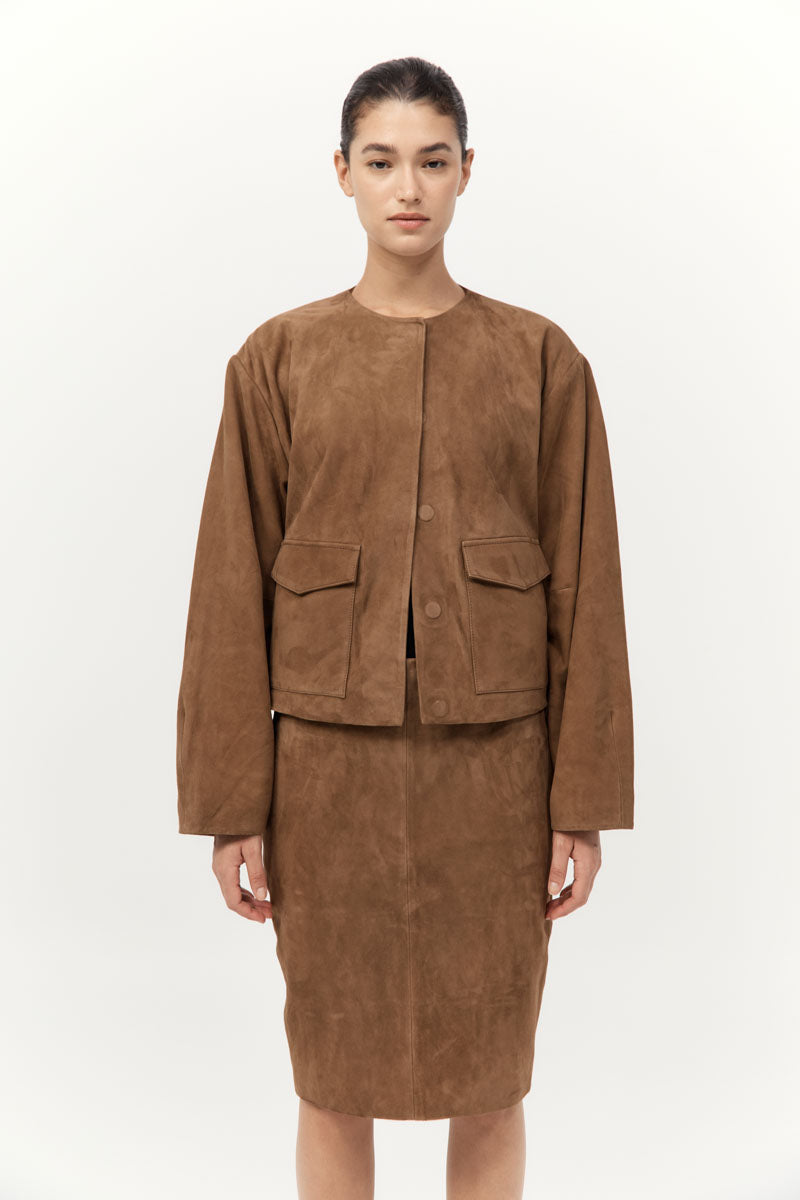Woman wearing a brown suede jacket and skirt set on a white background