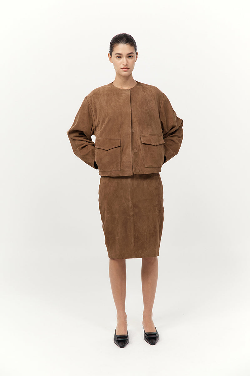 Person wearing a brown jacket and skirt set on a white background