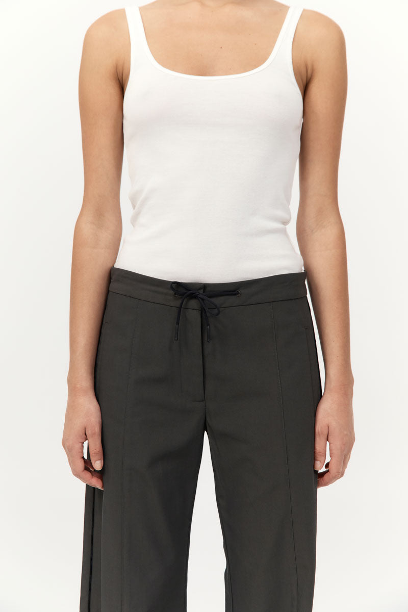 Person wearing a white tank top and black pants on a white background