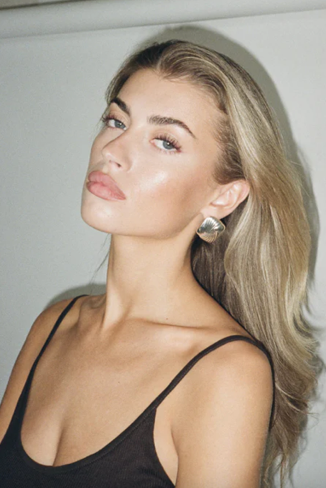 Woman with blonde hair wearing a black top against a white background