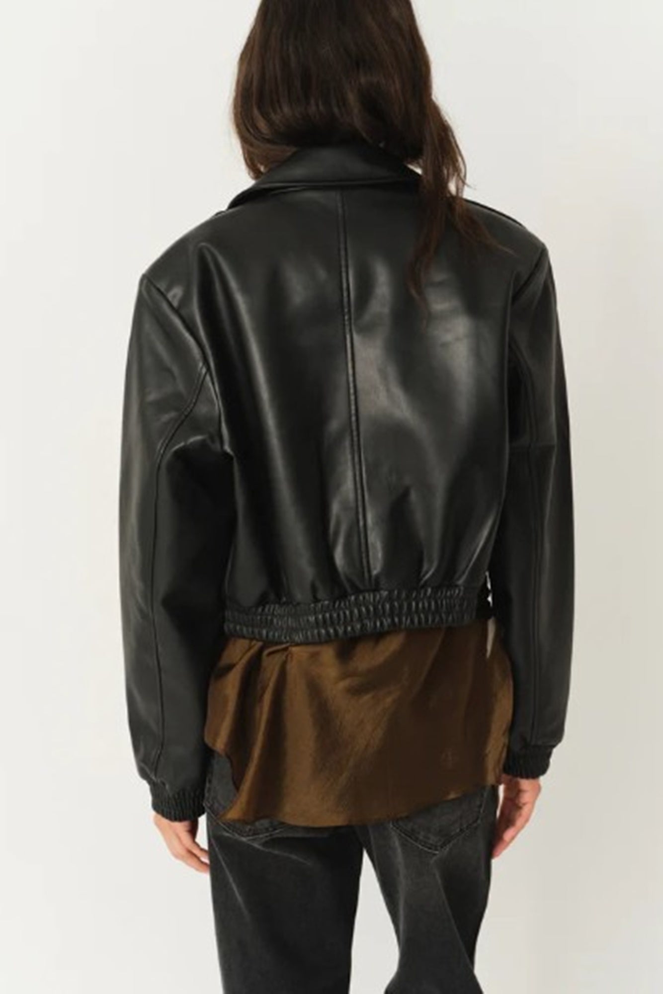 Person wearing a black leather jacket on a plain background