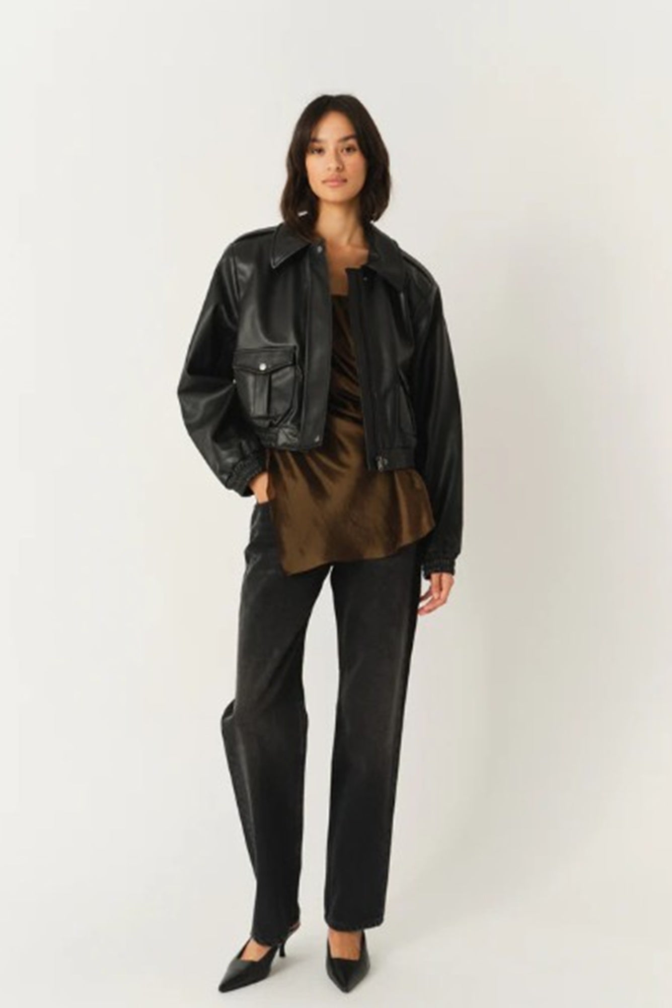 Person wearing a black leather jacket and pants on a white background