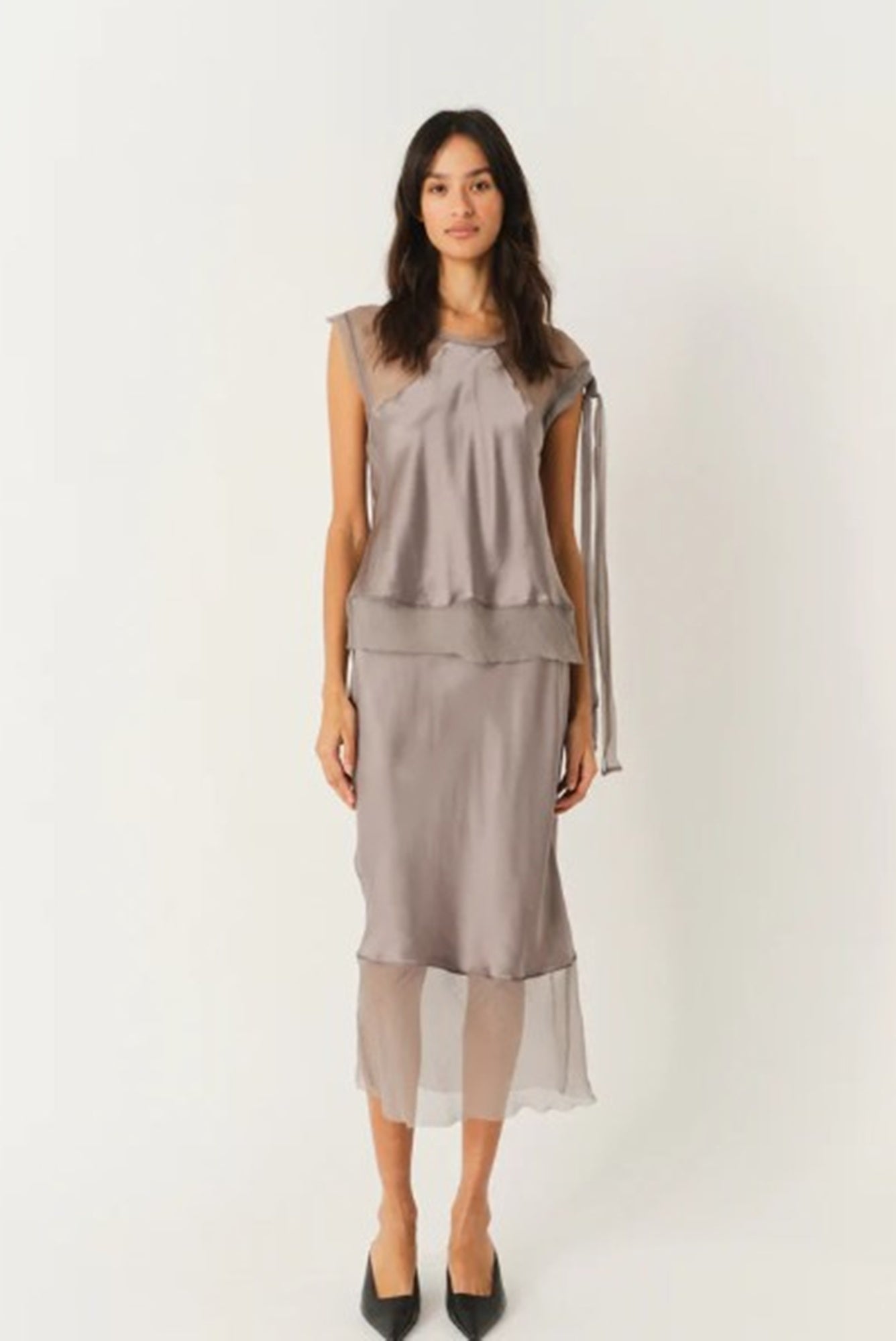 Woman wearing a gray sleeveless top and skirt set on a white background
