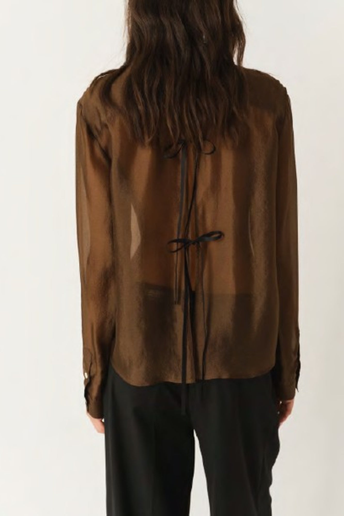 Brown sheer blouse with black drawstrings worn by a person on a white background