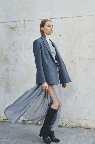 Woman wearing a long gray coat with a plain background