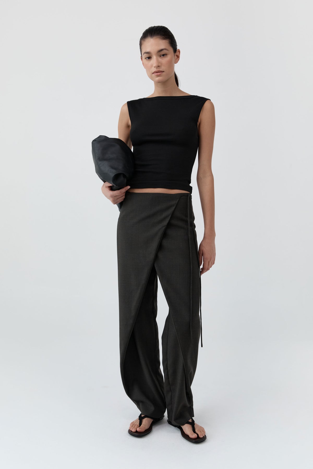 Woman wearing the St Agni Organic Cotton Ballerina Top-Jet Black with gray pants standing against a white background
