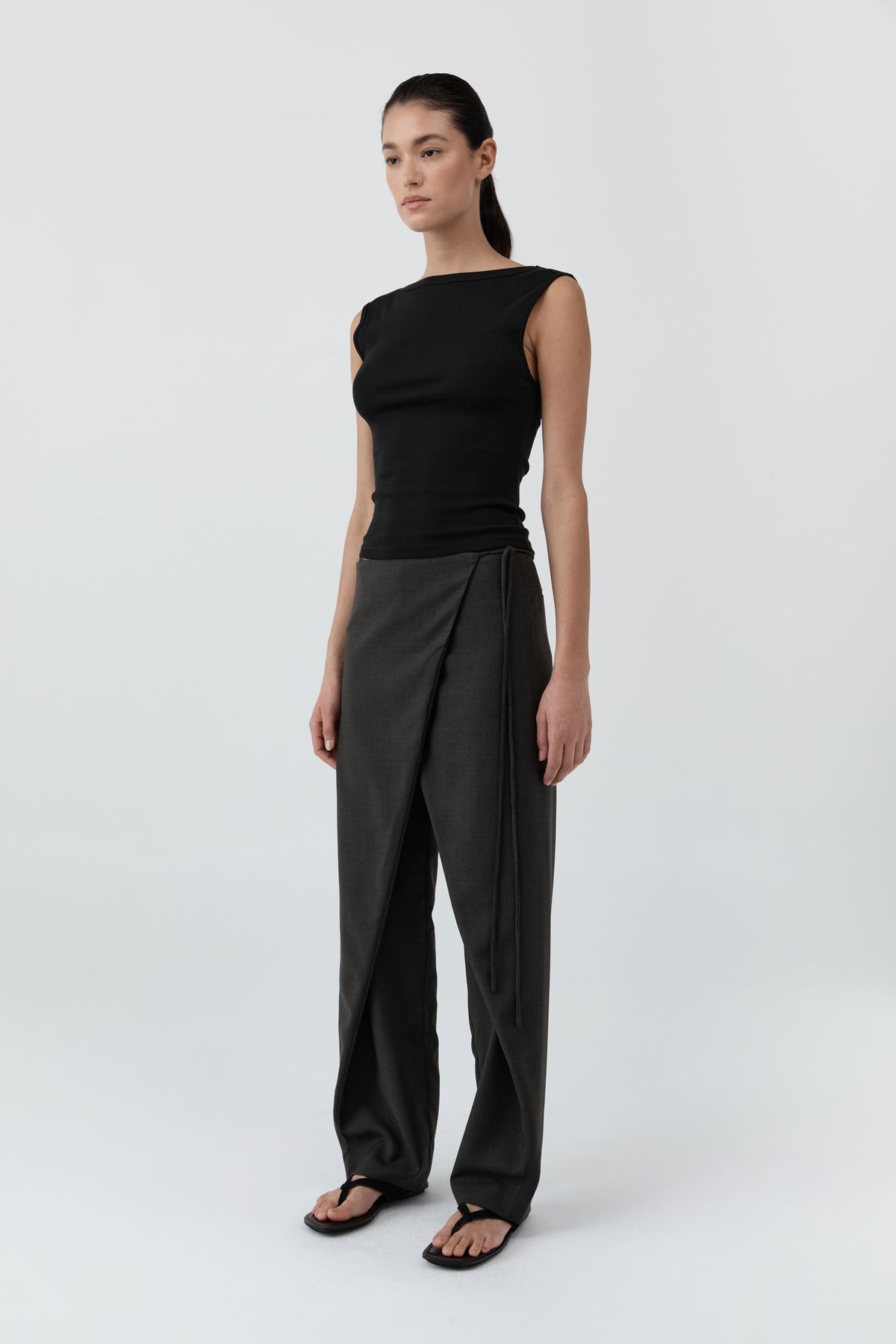Woman wearing the St Agni Organic Cotton Ballerina Top-Jet Black with gray pants standing against a white background