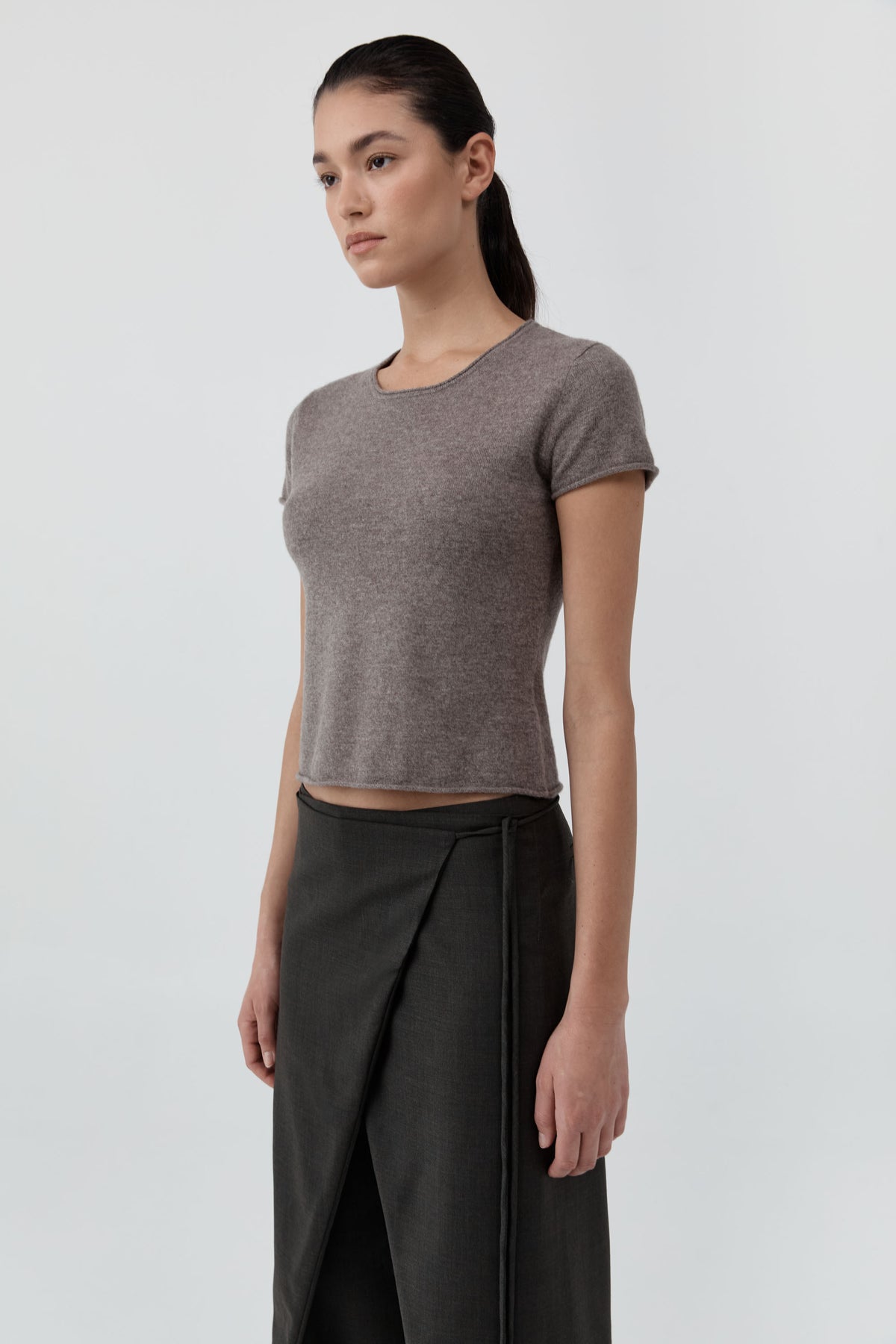 Woman wearing the St Agni Fine Merino Wool Baby Tee with black pants standing against a white background