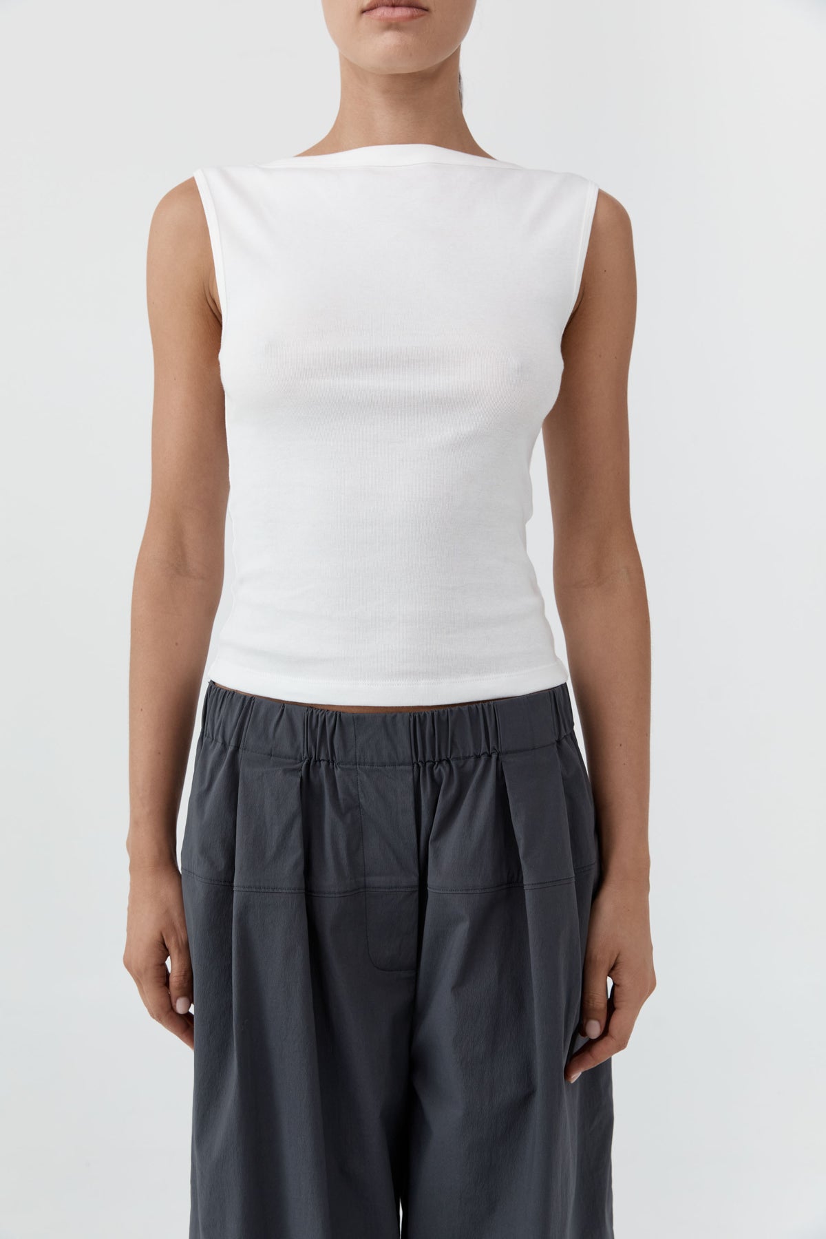 Woman wearing the St Agni Organic Cotton Ballerina Top-White and gray pants standing against a white background