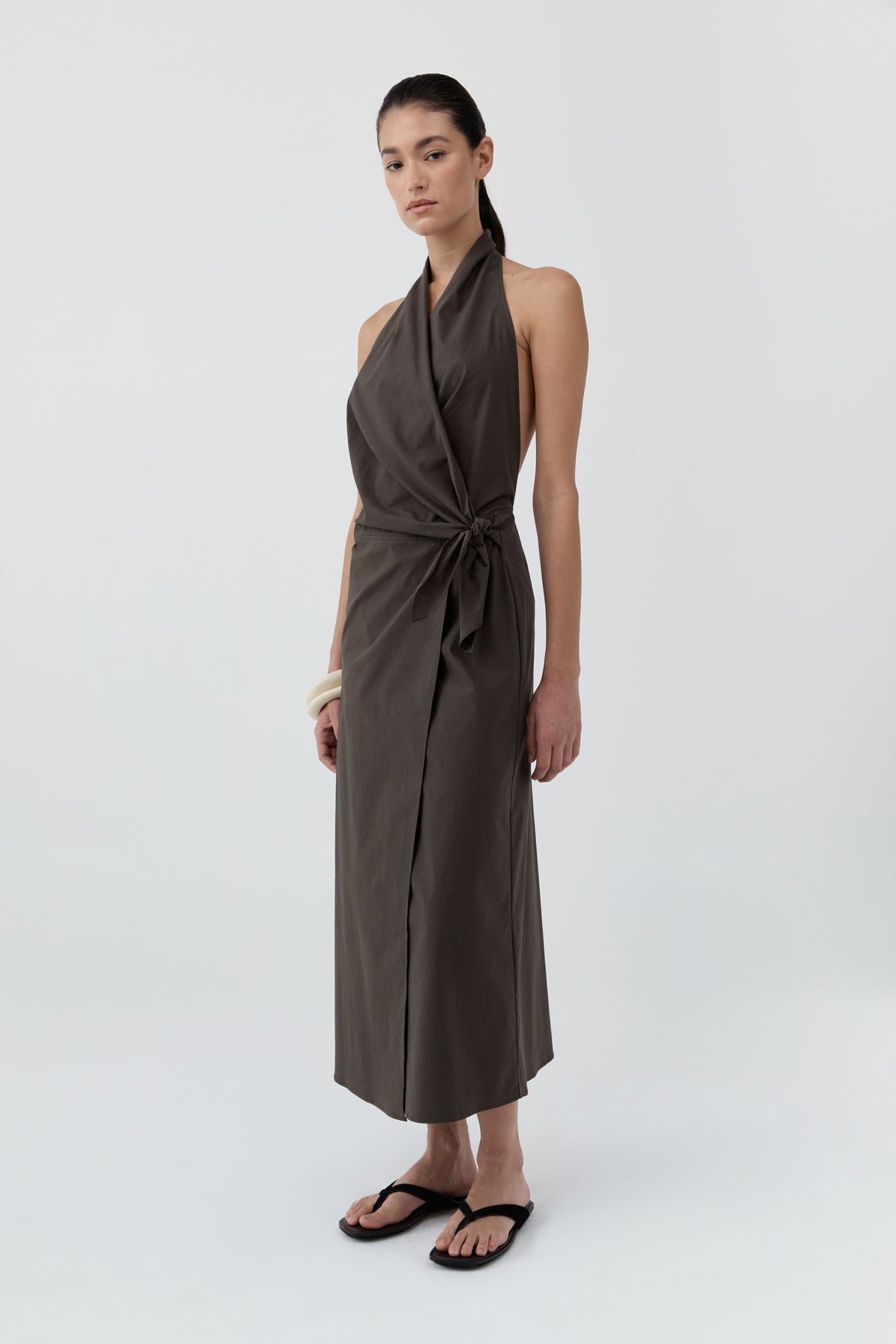 Woman wearing St Agni Halter Wrap Backless Dress standing against a white background