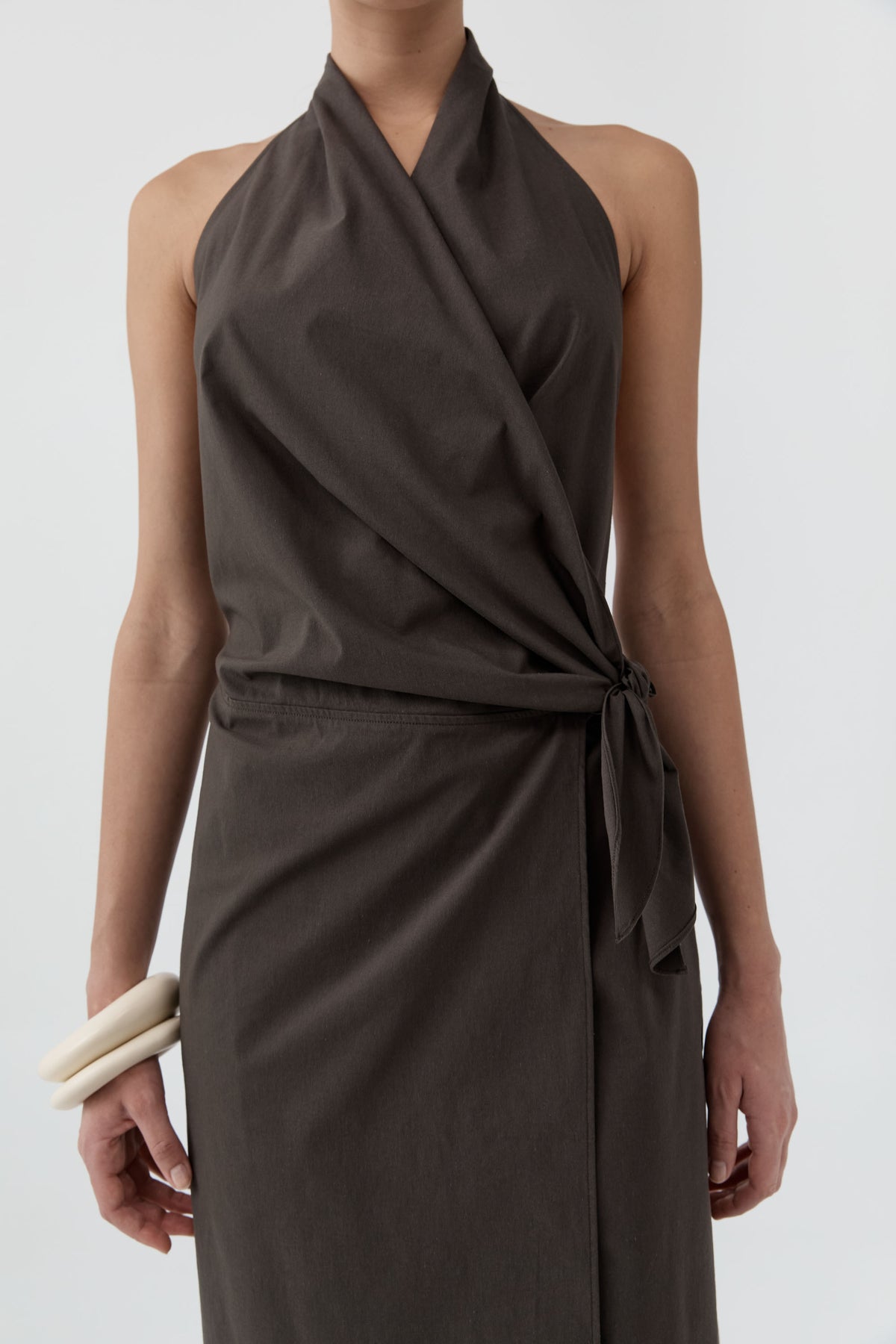 Close up of a woman wearing St Agni Halter Wrap Backless Dress standing against a white background
