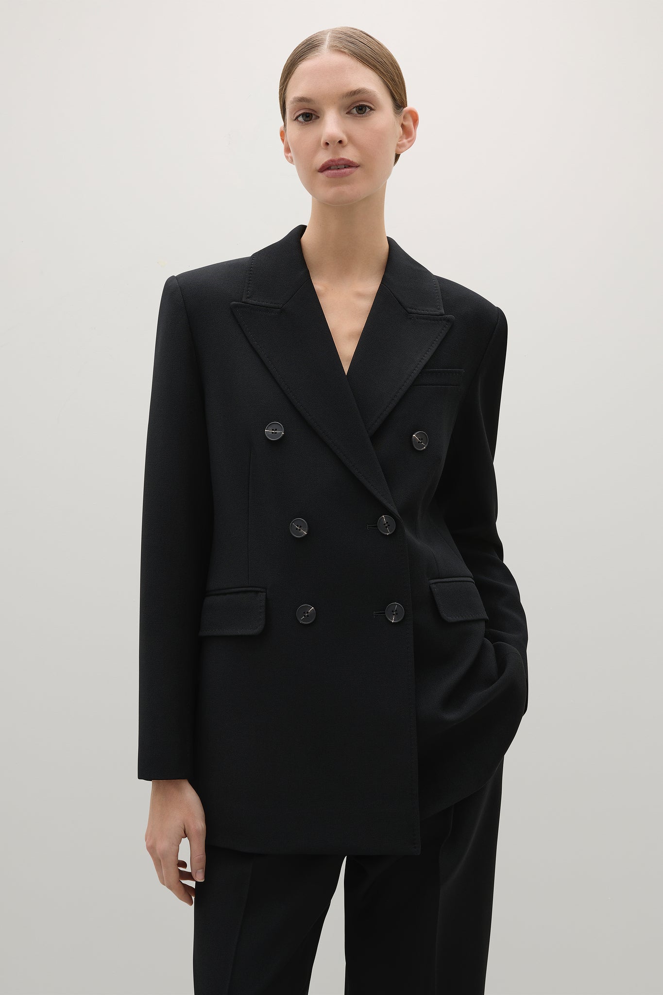 Person wearing a black double-breasted blazer against a plain background