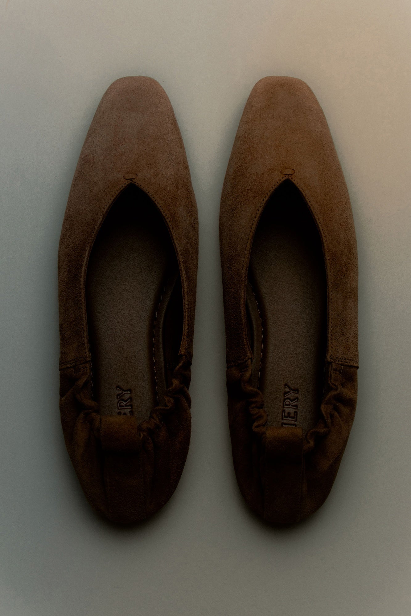 Pair of brown suede shoes on a light gray background