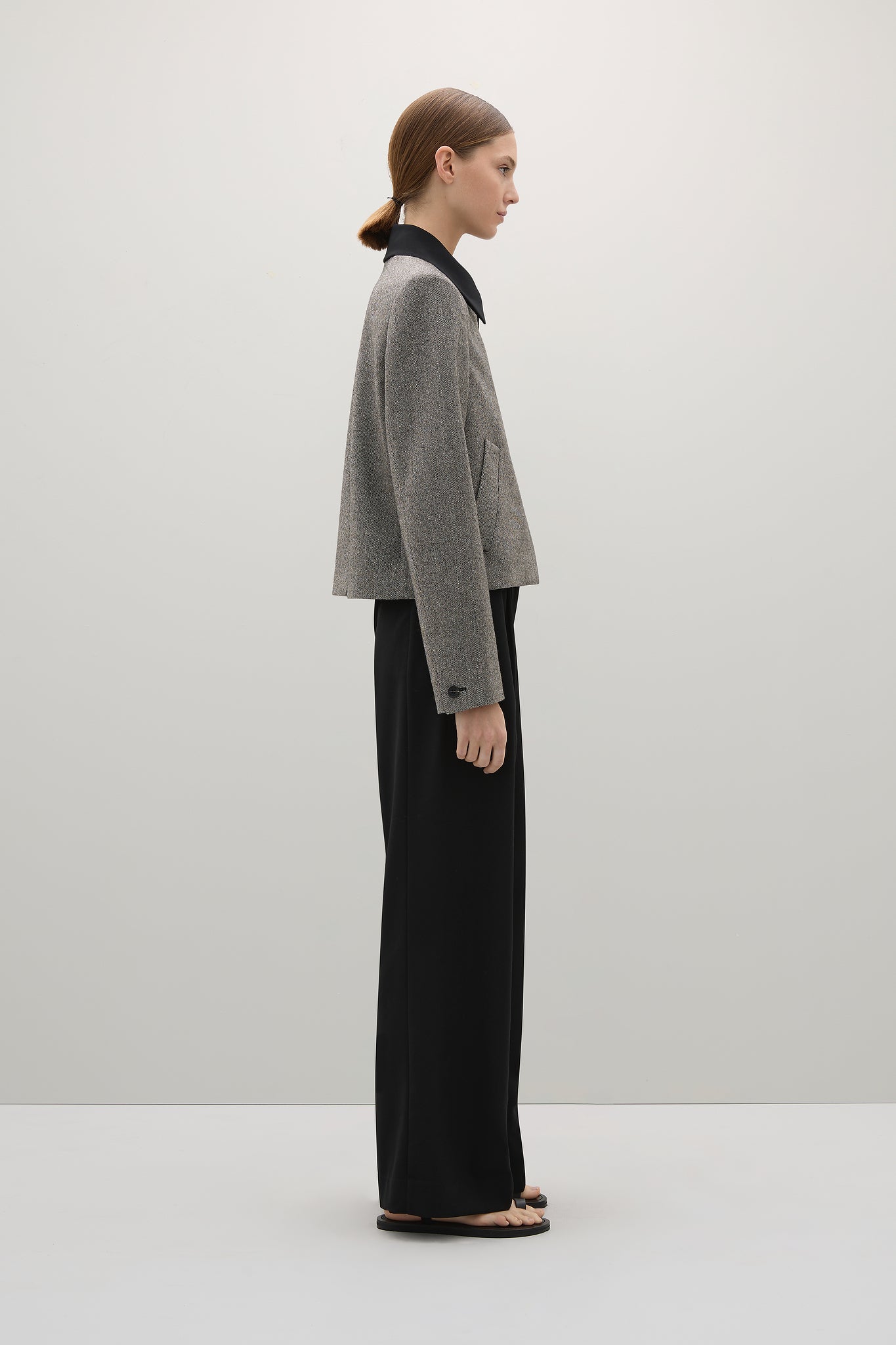 Woman wearing a gray sweater and black pants on a white background
