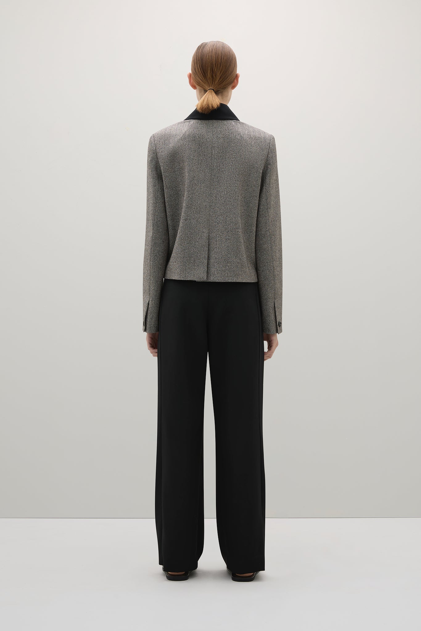 Person wearing a gray blazer and black pants on a white background