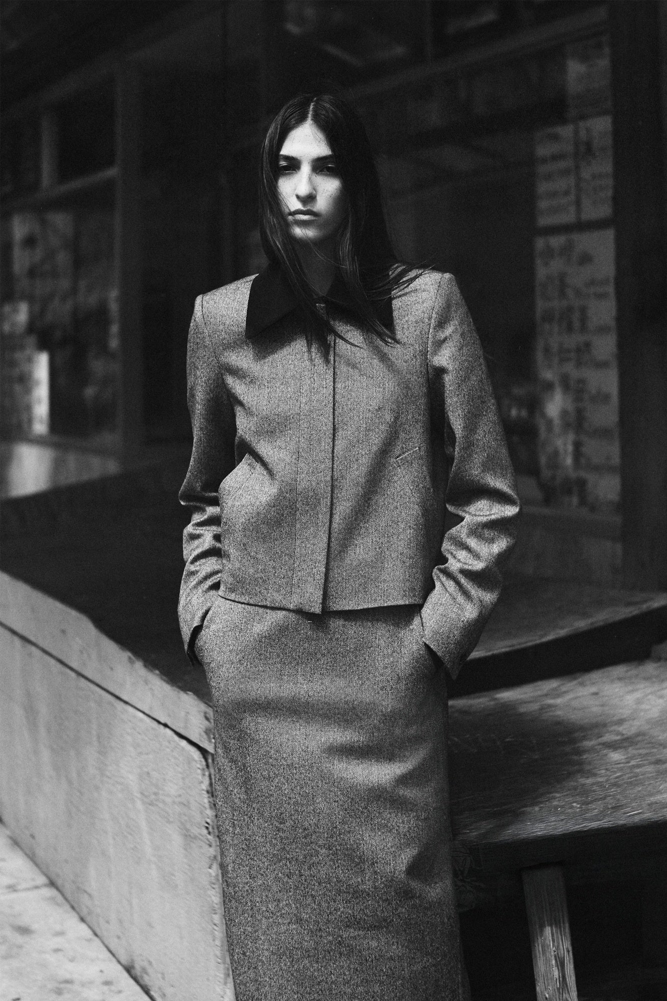 Person wearing a gray suit standing on a street corner.