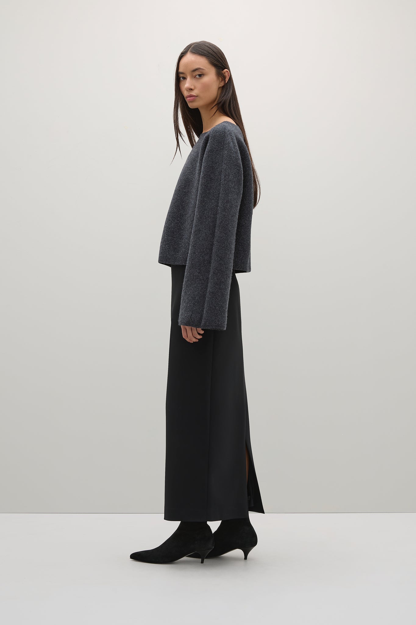 Woman wearing a gray sweater and black skirt on a white background