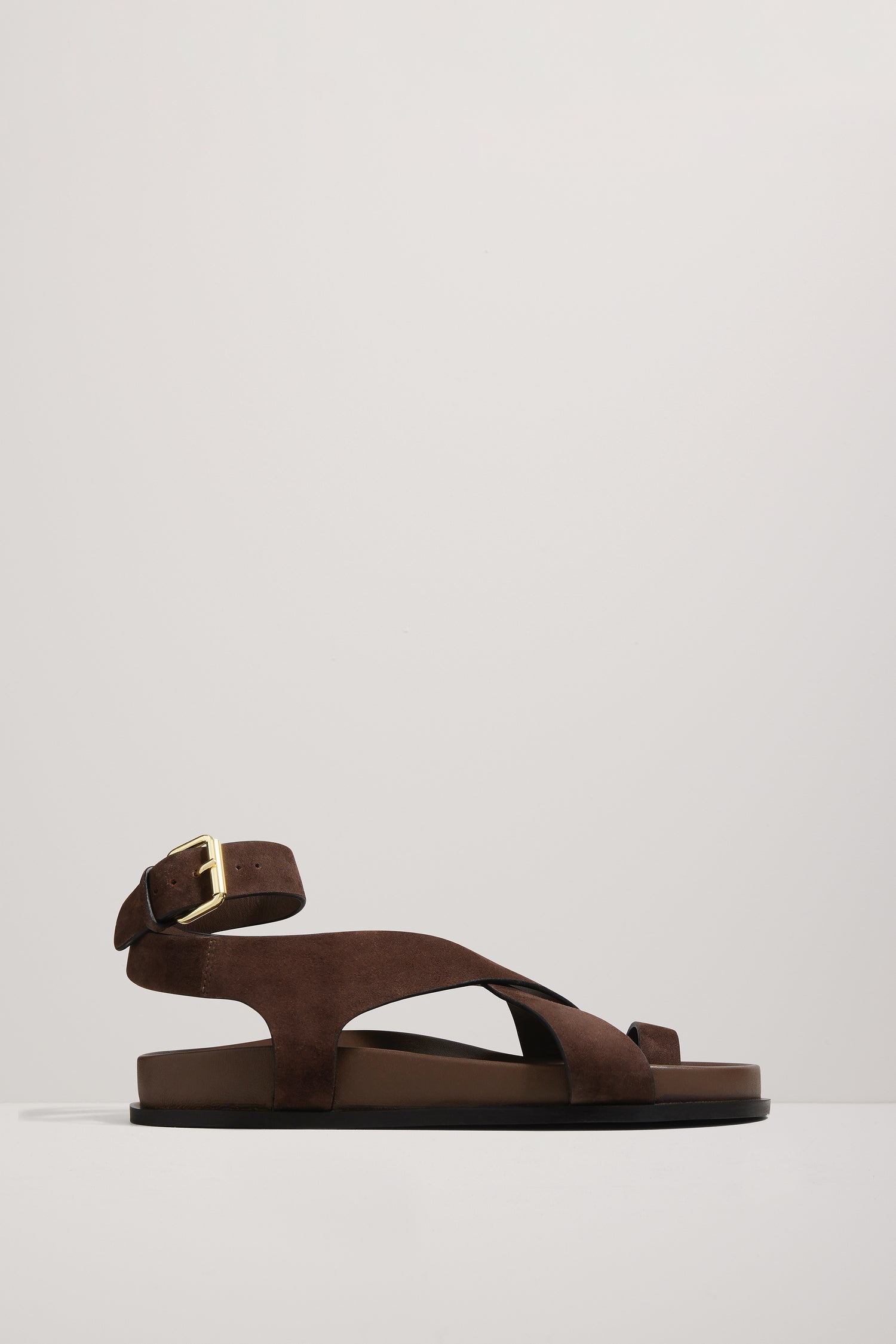 Brown sandal with a gold buckle on a light gray background