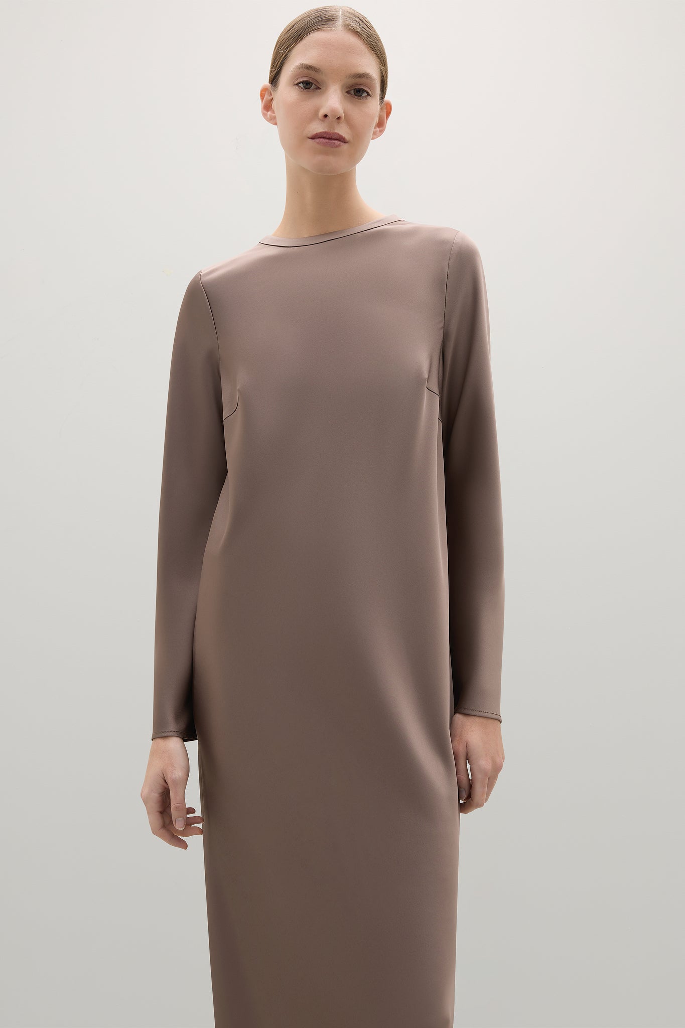 Woman wearing a brown dress against a plain background