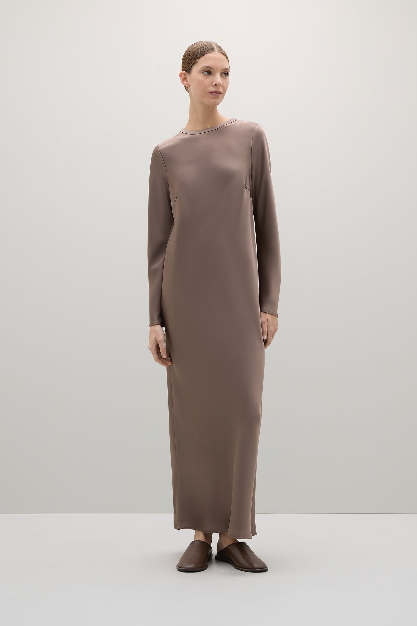 Woman wearing a long brown dress on a white background