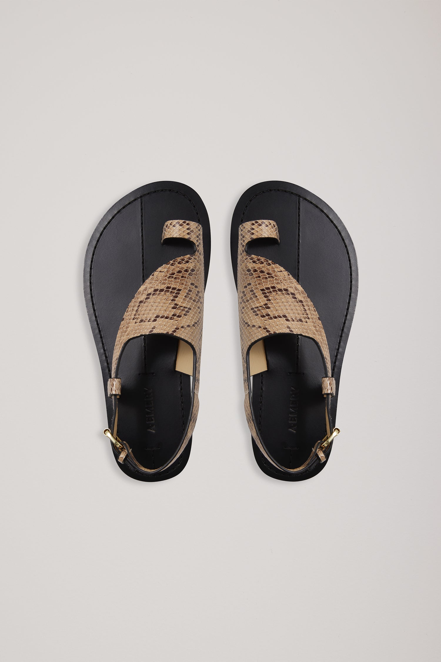 Pair of sandals with snake print straps on a light gray background
