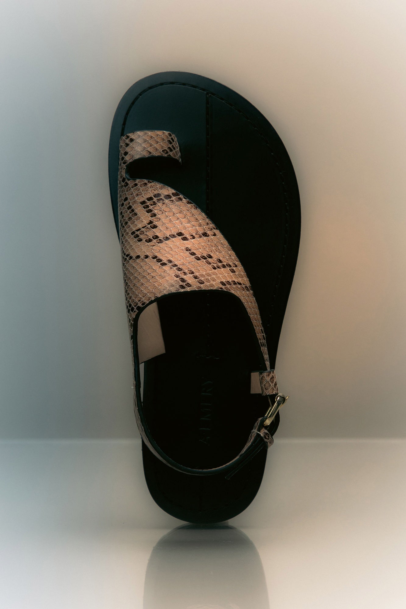 Black sandal with snake print strap on a white background